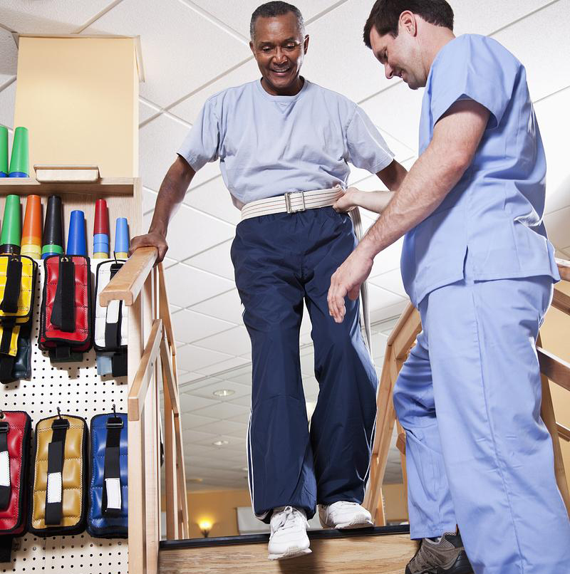 Physical therapist with senior man climbing stairs